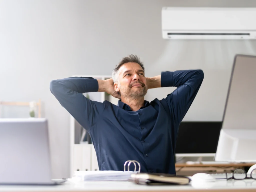 A homeowner sits next to their newly installed AC unit, happy with their air conditioner upgrade.